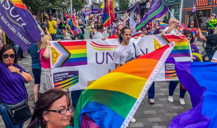 Pride parade participants carrying rainbow flags and banners through Ballymena town centre